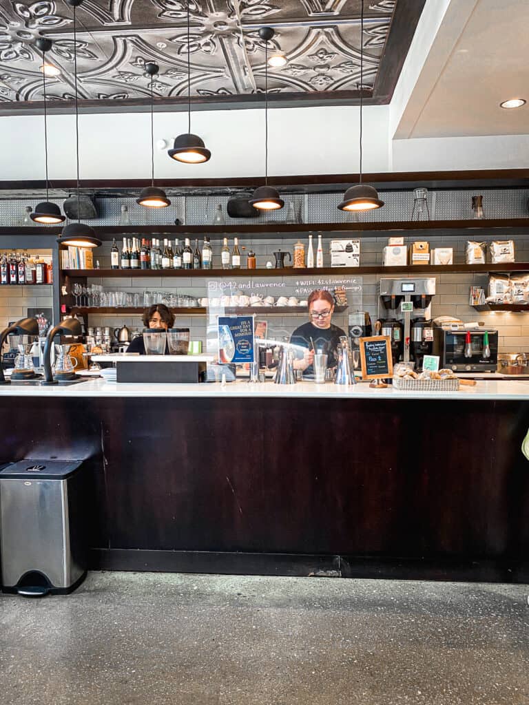 a modern coffee bar with dark wood and white walls while a barista makes a coffee