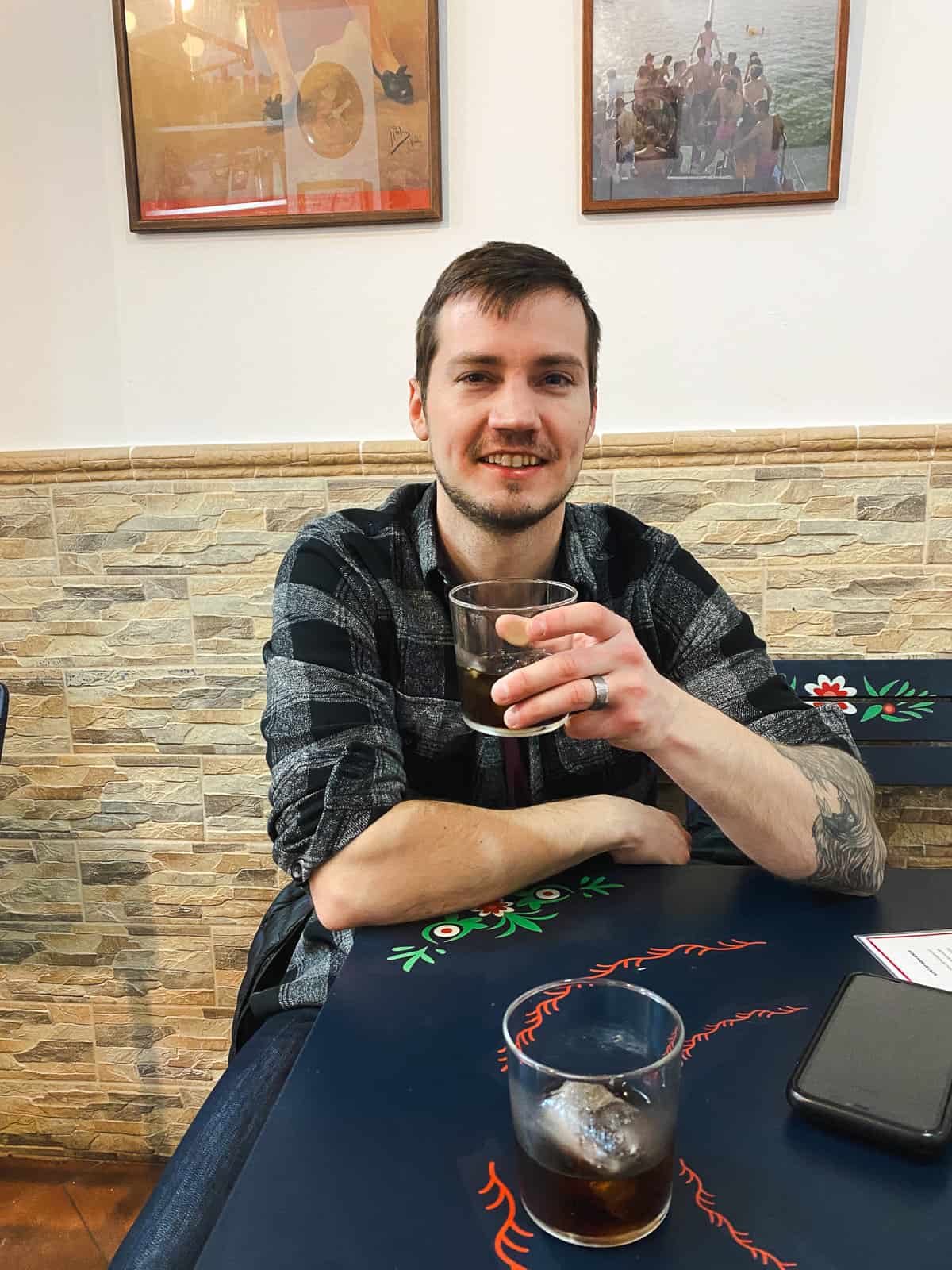 A man holding a glass of vermouth in a small, brick tapas bar in Madrid Spain