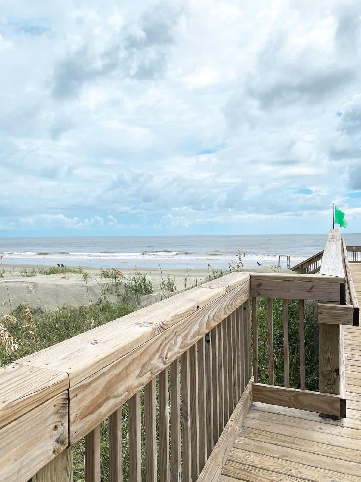 A wooden pier on the beach with a blue cloudy sky 