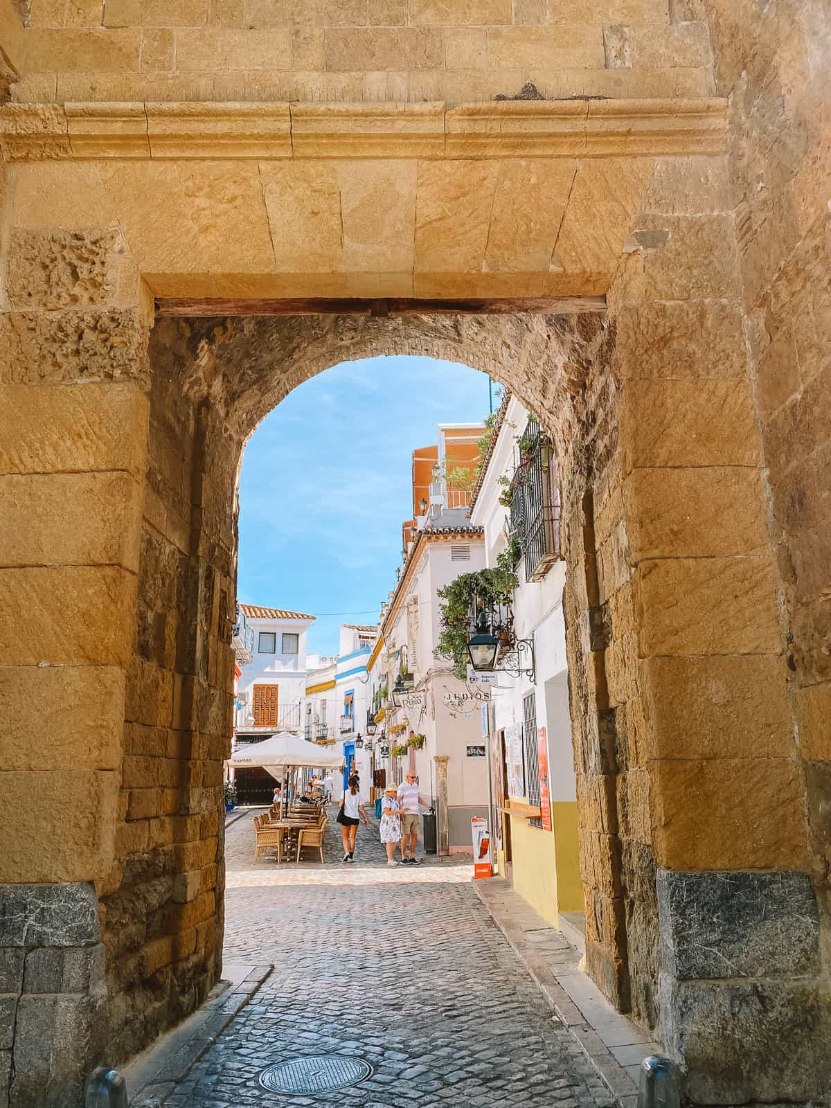 a brownstone archway looking into a street with white buildings
