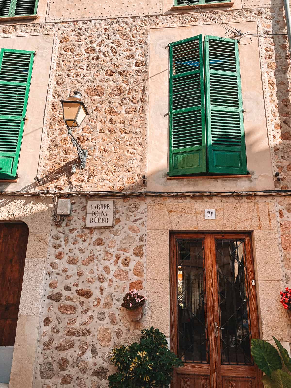 a small cobblestone alley with brownstone buildings and green shutteres
