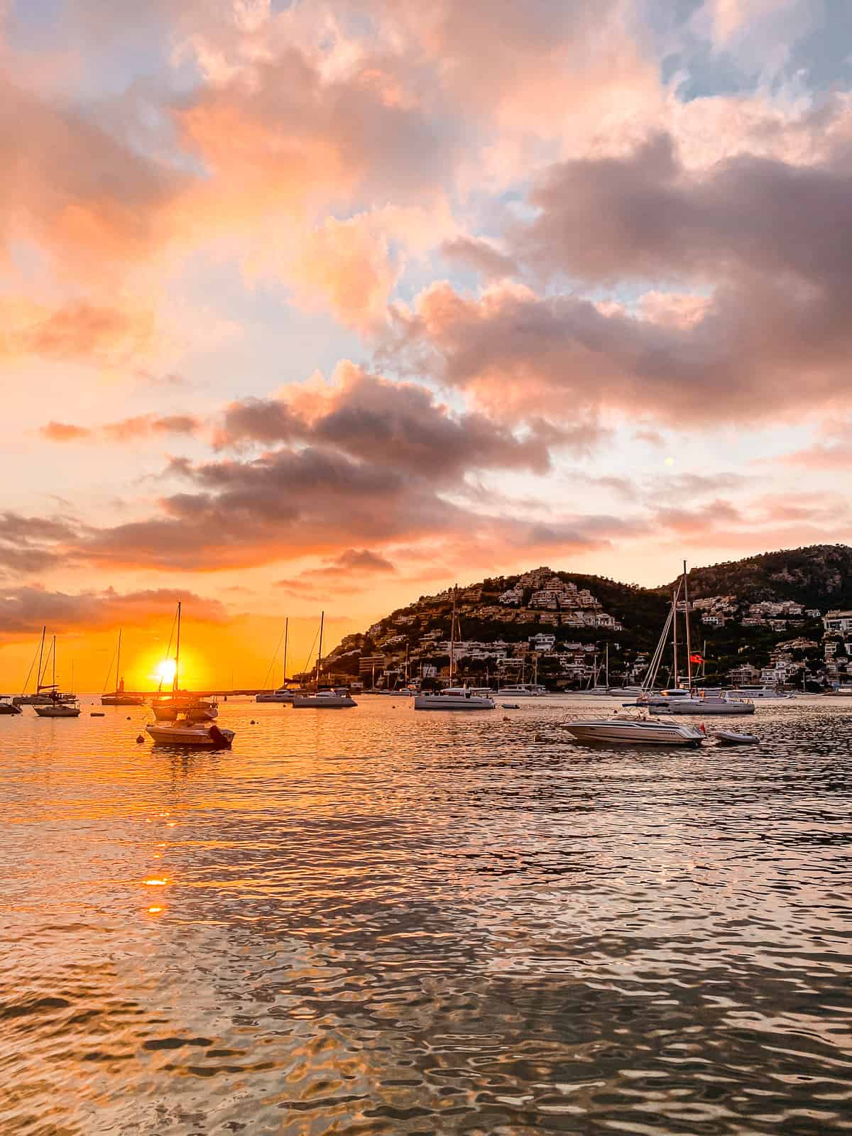 An orange and pink sunset over a harbor with a yacht