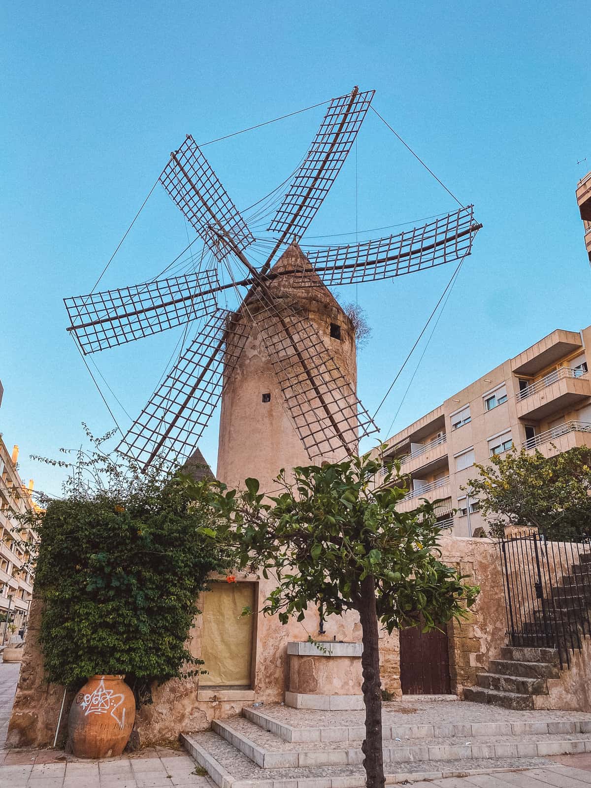 A large windmill on.a brick street with a blue sky