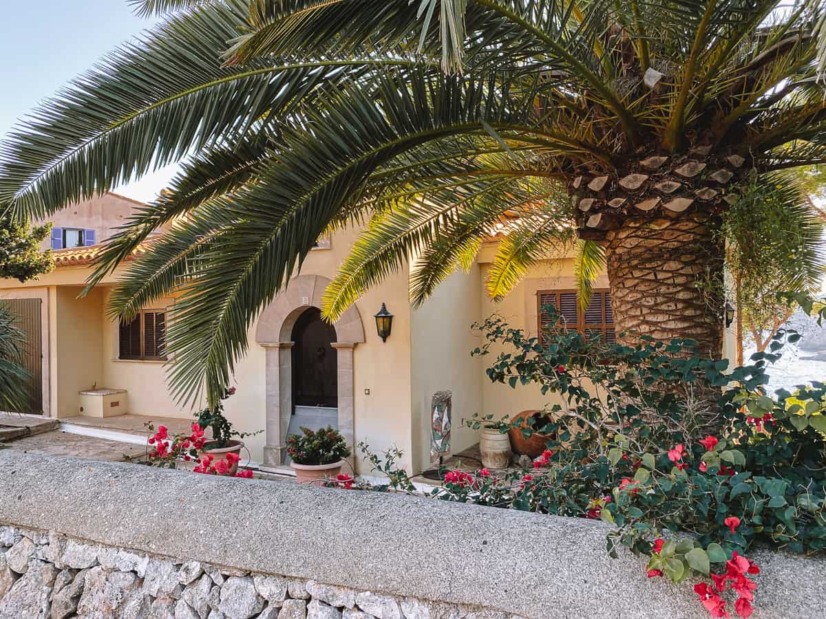 a tropical white stone building with palm trees and flowers