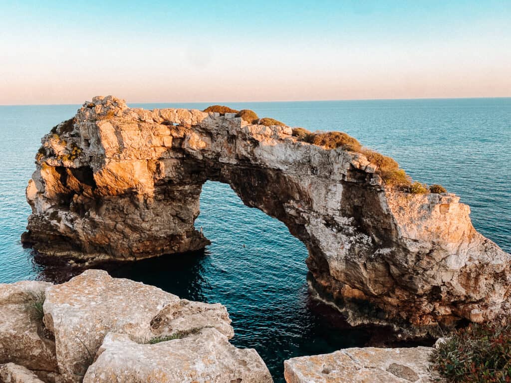 an arched rock formation in the water