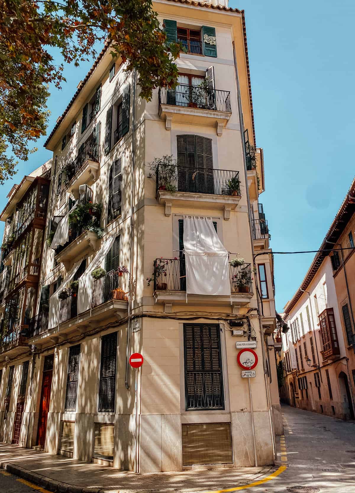 a tall brown building with 2 balconies on a cobblestone street
