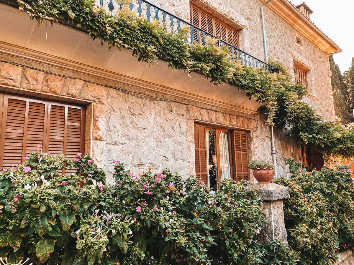 an old stone building lined with leaves and pink flowers