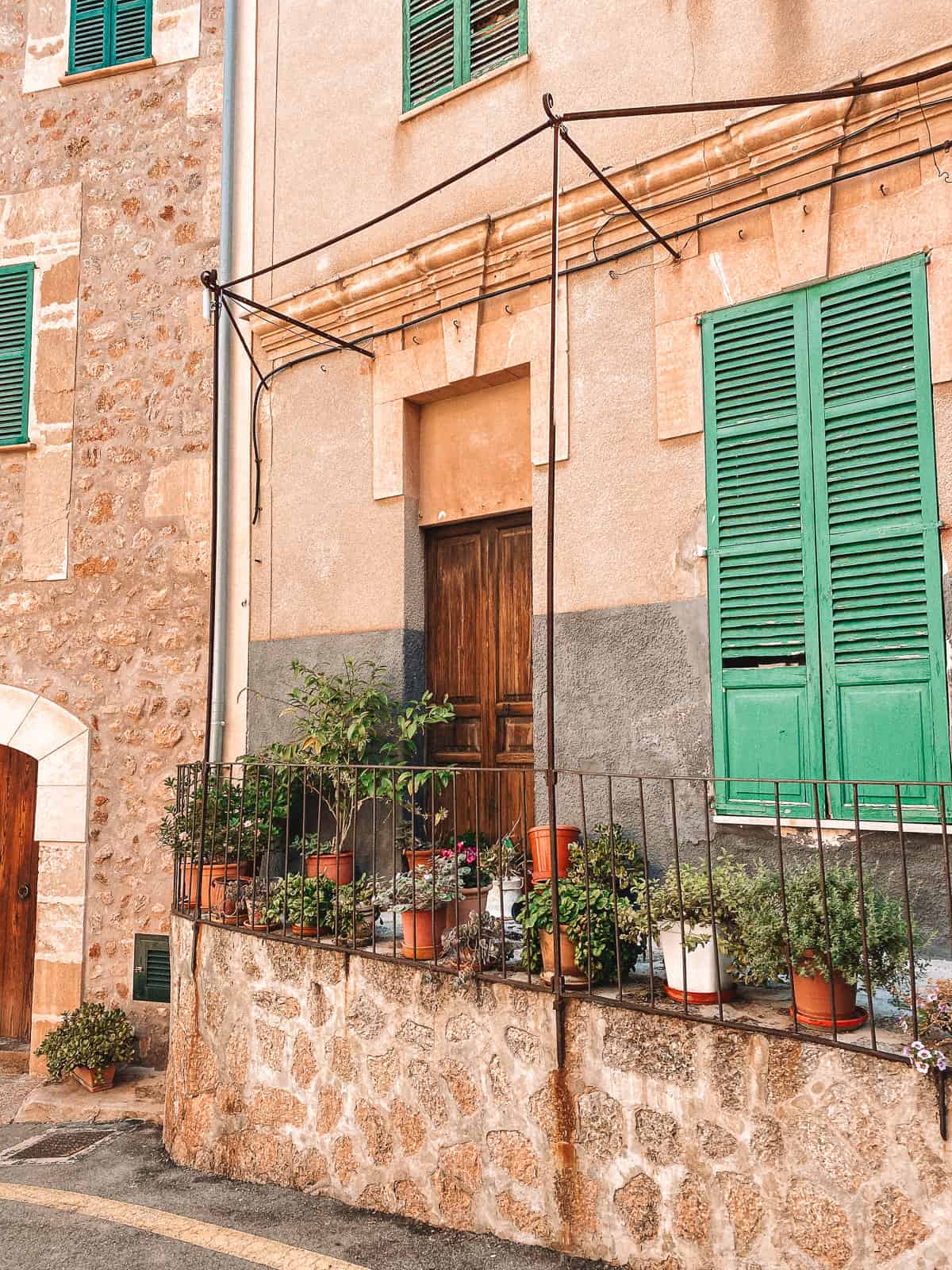 An antique brown door with lowers and a green shutter on the window beside it