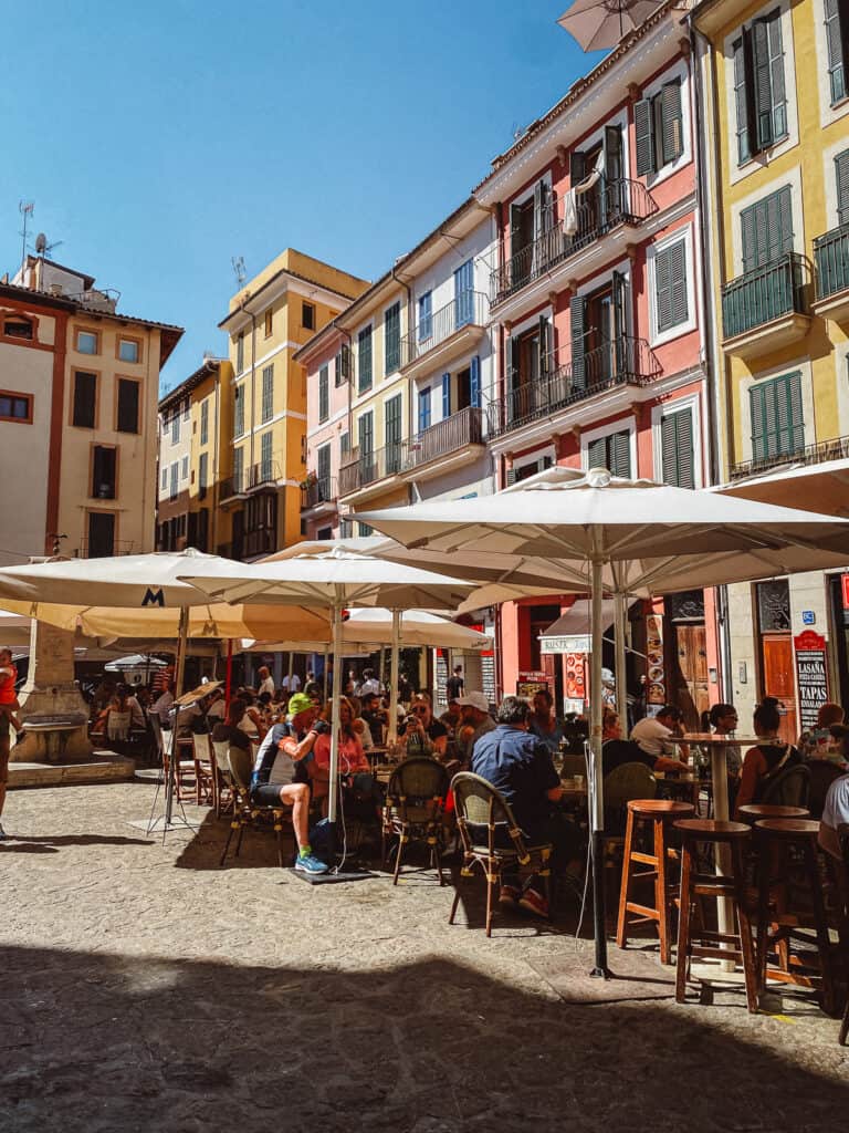 A colorful street with tables and people sitting at it having lunch