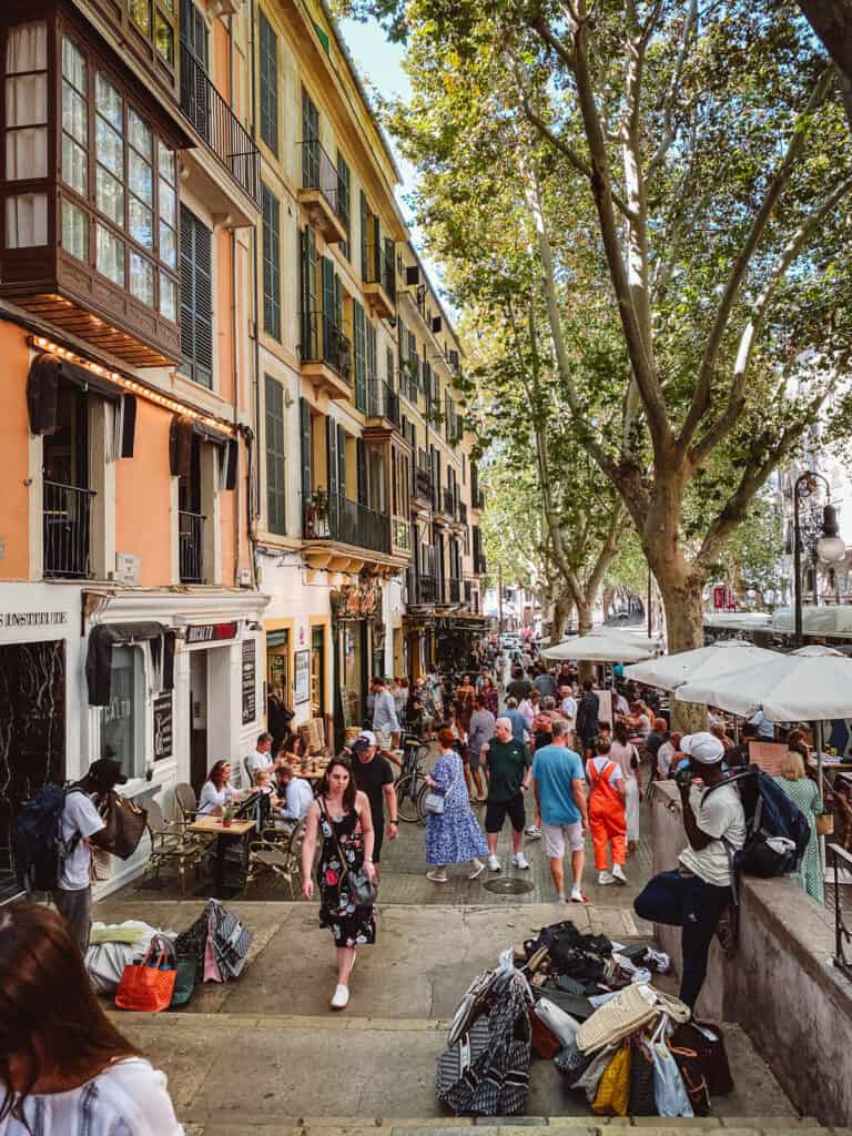 a colorful street with hordes of tourists walking down it in Mallorca, Spain