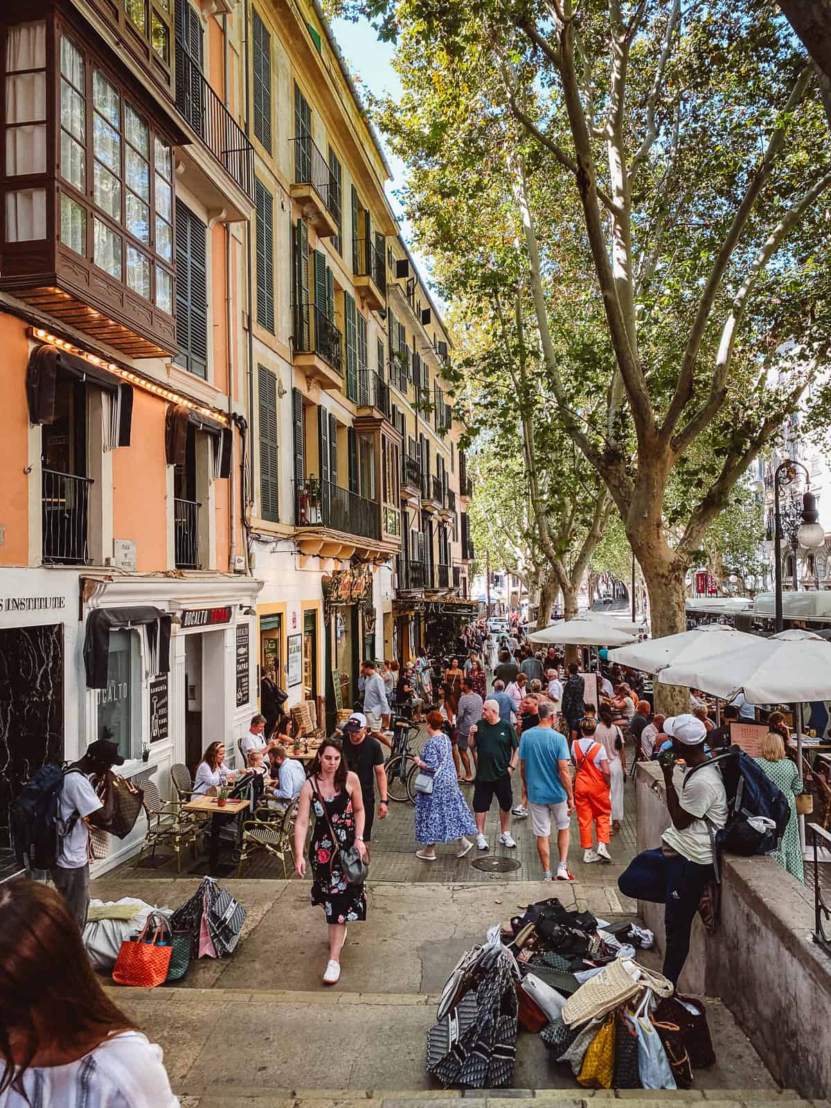a colorful street with hordes of tourists walking down it in Mallorca, Spain