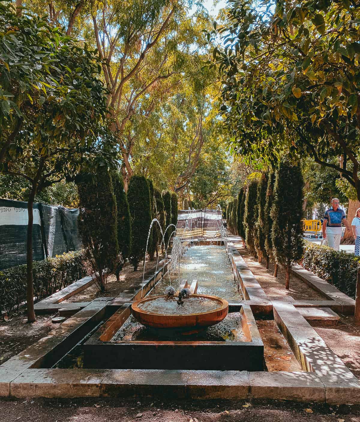 a fountain on a cement platform surrounded by green trees