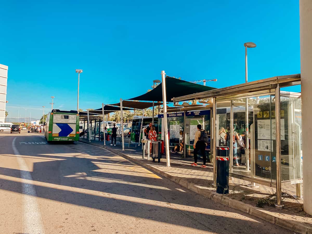 A bus station outside an airport with people waiting