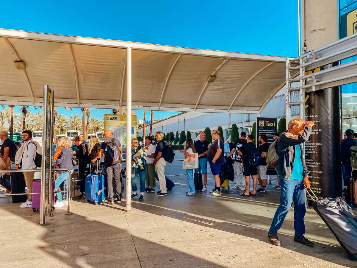People standing at a taxi stand outside an airport