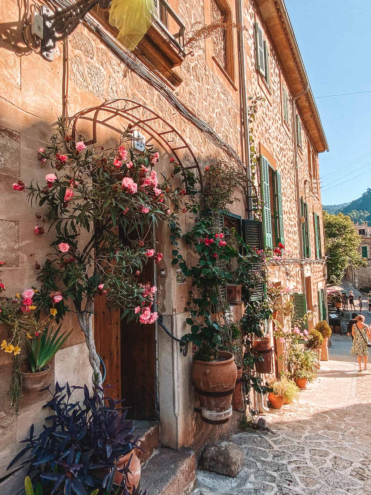 a beautiful stone building with a door and pink flowers
