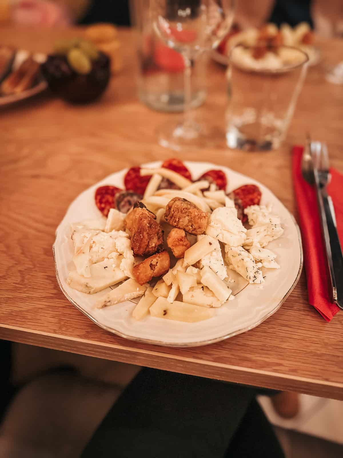 a plate of delicious sausage and cheese on a wooden table with a glass of wine