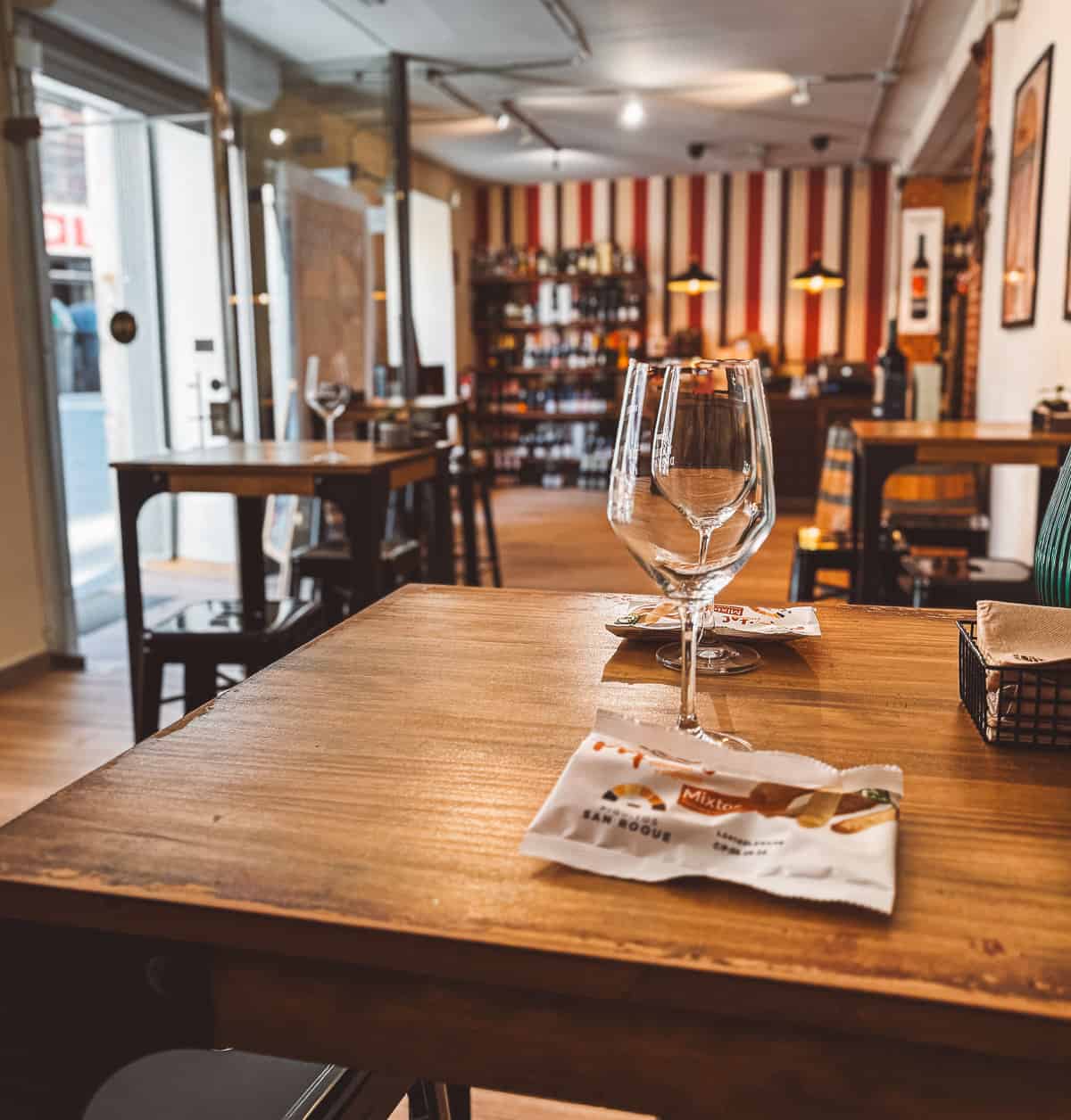 An empty wine glass sits on a wooden table in a wine shop in Madrid