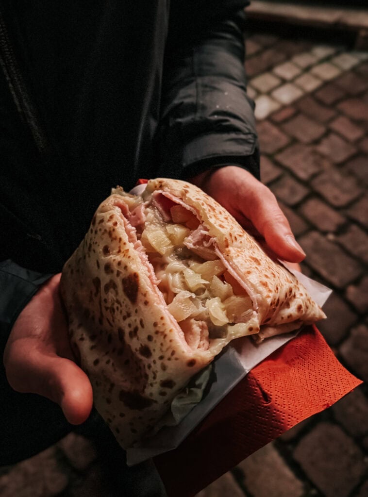a hand holding a savory ham and cheese and pineapple crepe