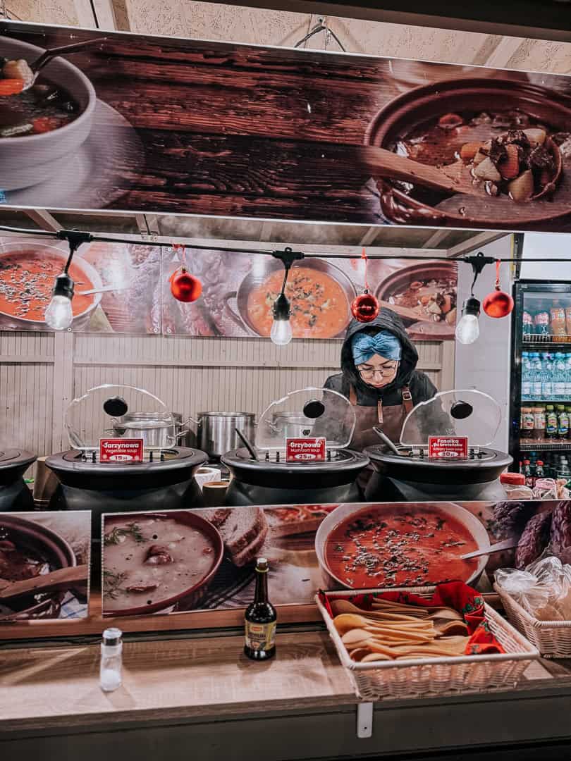 Mulled wine station with signage offering various hot beverages and holiday specials at a Krakow Christmas market.