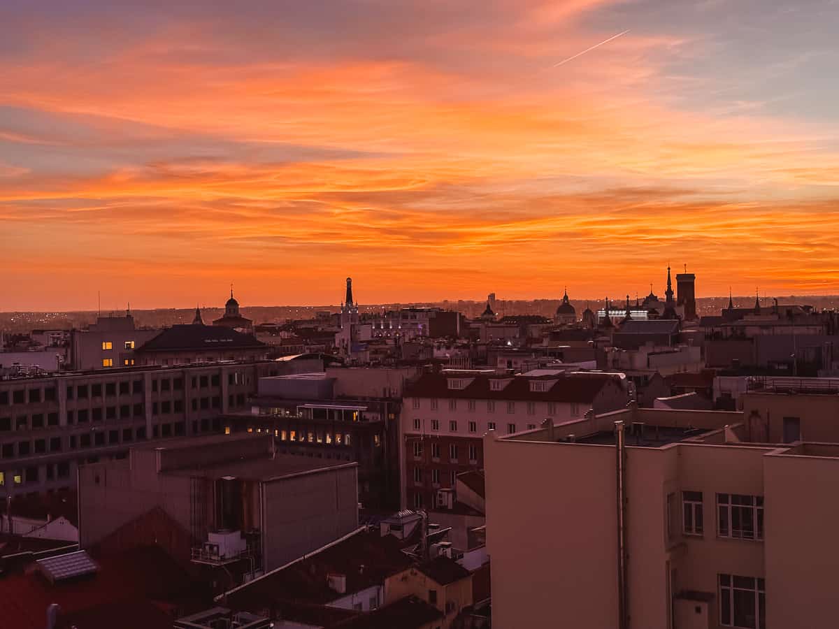 A breathtaking sunset over a cityscape, with the sky painted in vibrant shades of pink and orange, silhouetting the urban skyline with warm, luminous hues.