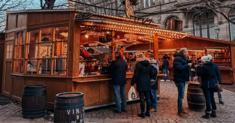 A charming Christmas market booth offering a variety of crafts under the glow of festive lights, with shoppers browsing the items