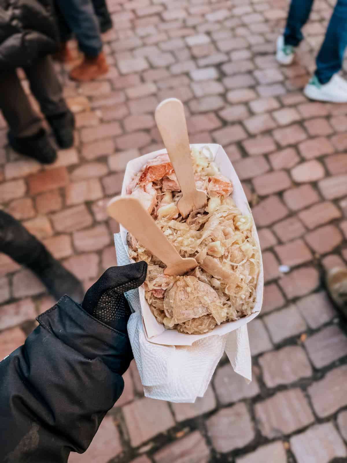 a paper bowl of sauerkraut mixed with sausage