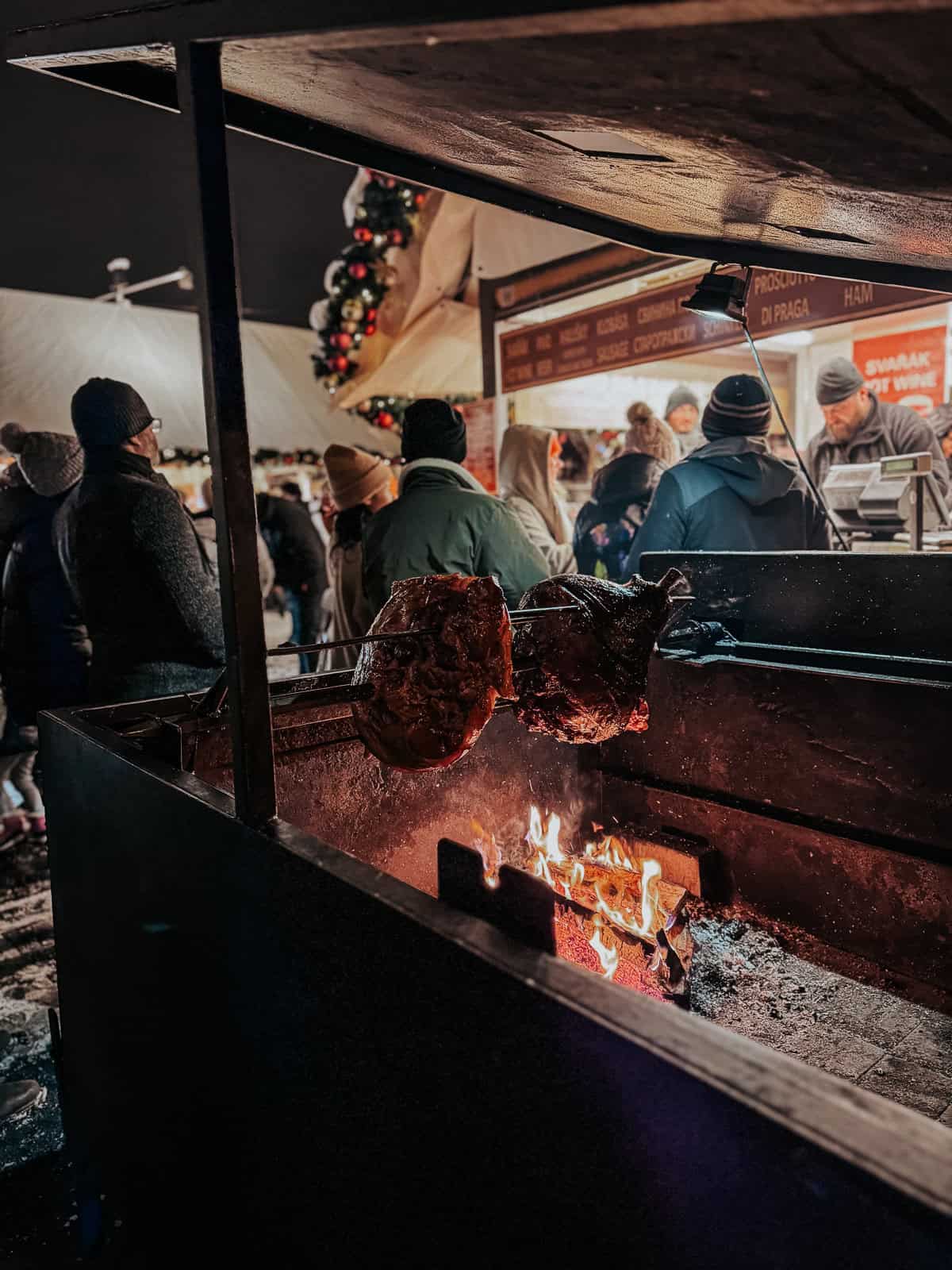 A large ham being roasted on a spit over an open fire