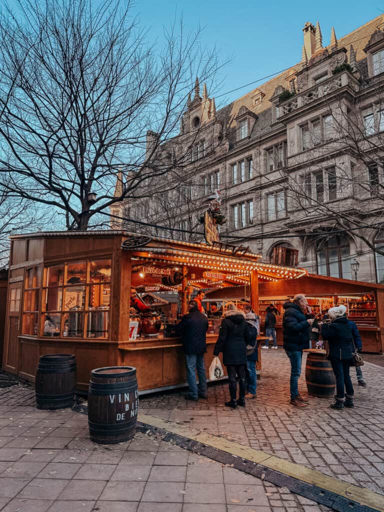 A charming Christmas market booth offering a variety of crafts under the glow of festive lights, with shoppers browsing the items