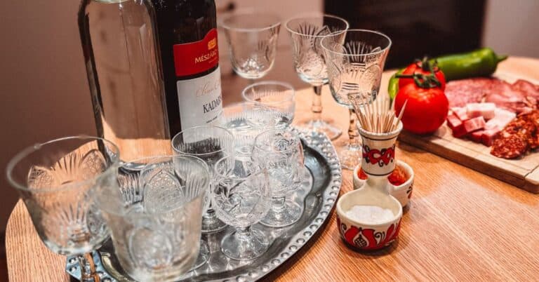 a tray with vegetables and Hungarian meat with wine glasses in the foreground