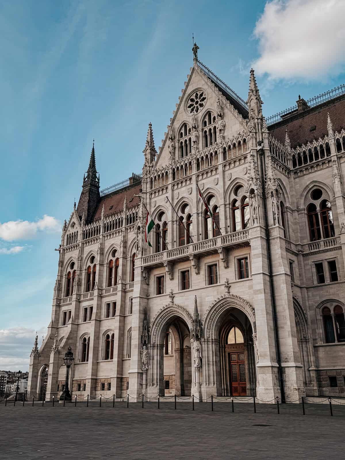 A close-up view of the ornate facade of the Hungarian Parliament Building in Budapest, showcasing its Gothic Revival architecture against a blue sky.