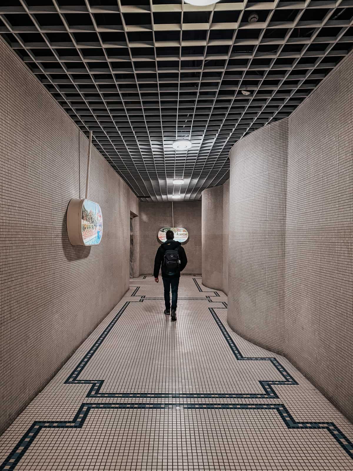 Corridor in the Gellért Thermal Bath, with a man walking towards the end under a tiled ceiling.
