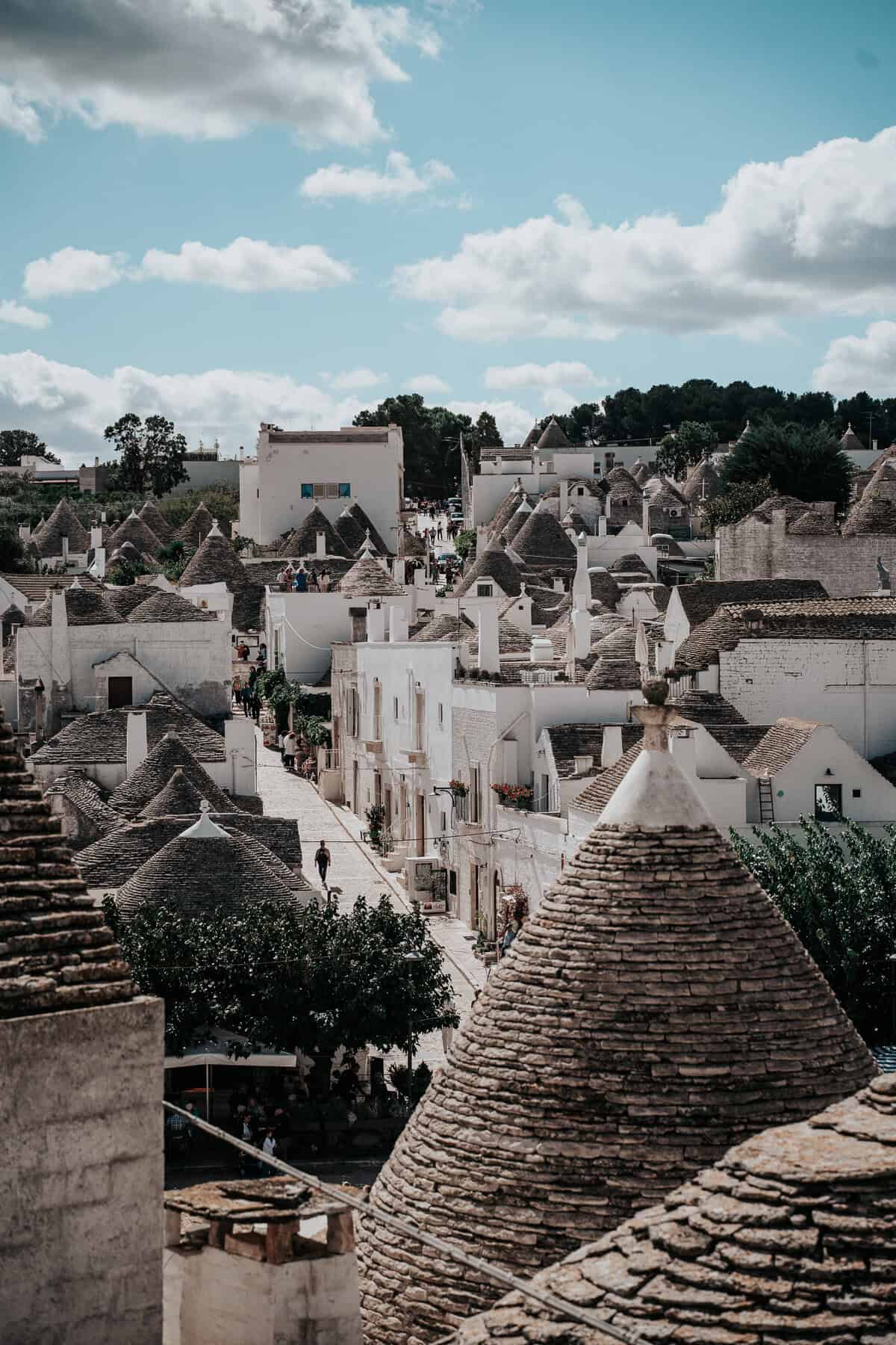 A charming street in Alberobello, Italy, lined with traditional Trulli houses featuring conical stone roofs, a UNESCO World Heritage site.