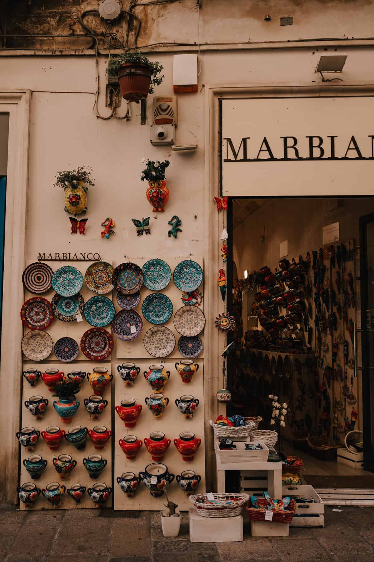 A picturesque Italian market stall selling colorful handcrafted ceramics, including plates, bowls, and decorative vases.