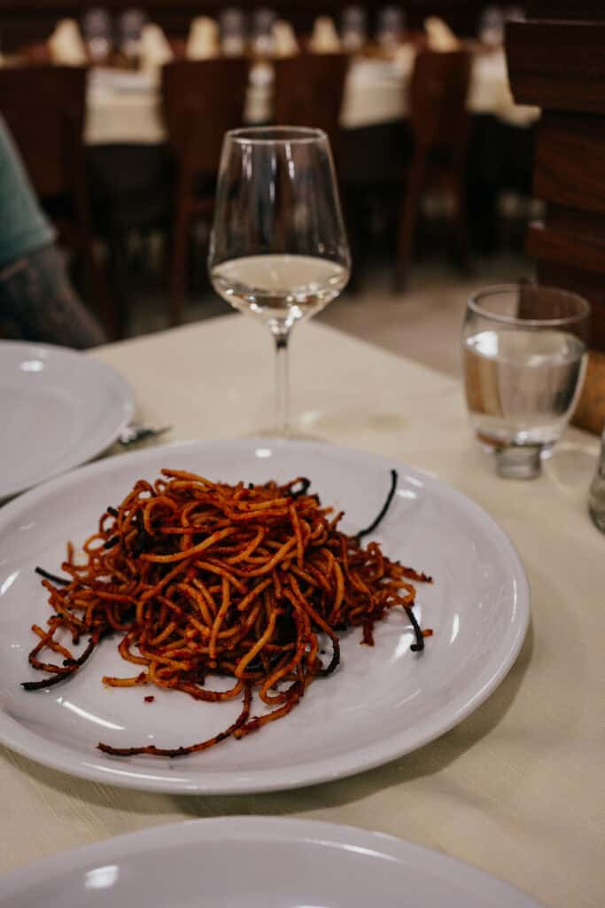 A plate of Spaghetti all’Assassina, a traditional dish from Bari, Italy, featuring caramelized, crispy pasta cooked in a rich, spicy tomato sauce.