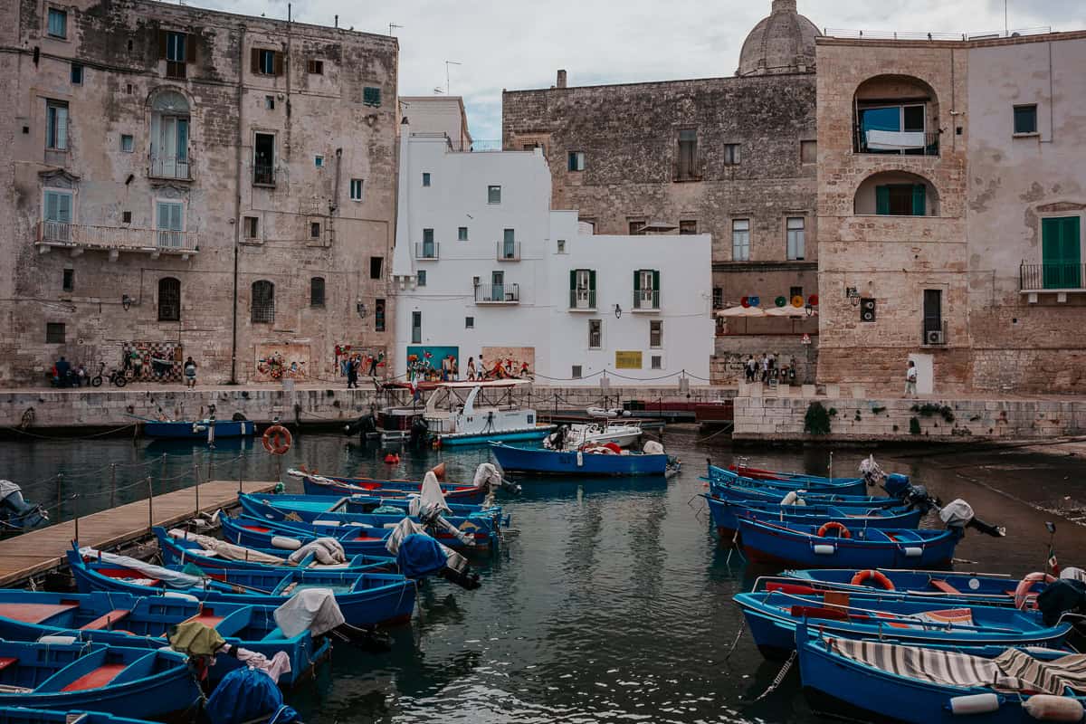 the harbor of Monopoli with stone buildings and cute, blue boats lining the harbour