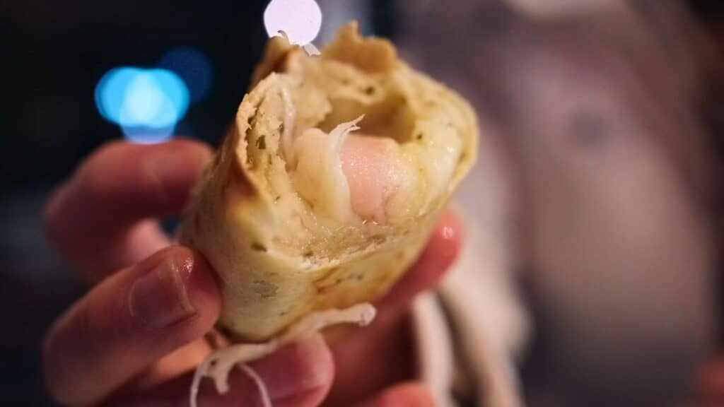 Close-up of a French-style empanada filled with ham and melted cheese, eaten as street food in Lyon