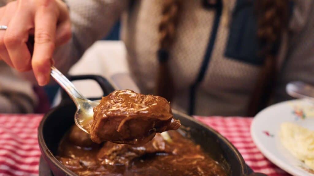 Braised pork cheeks in rich Lyonnaise onion sauce served with vegetables at a traditional bouchon