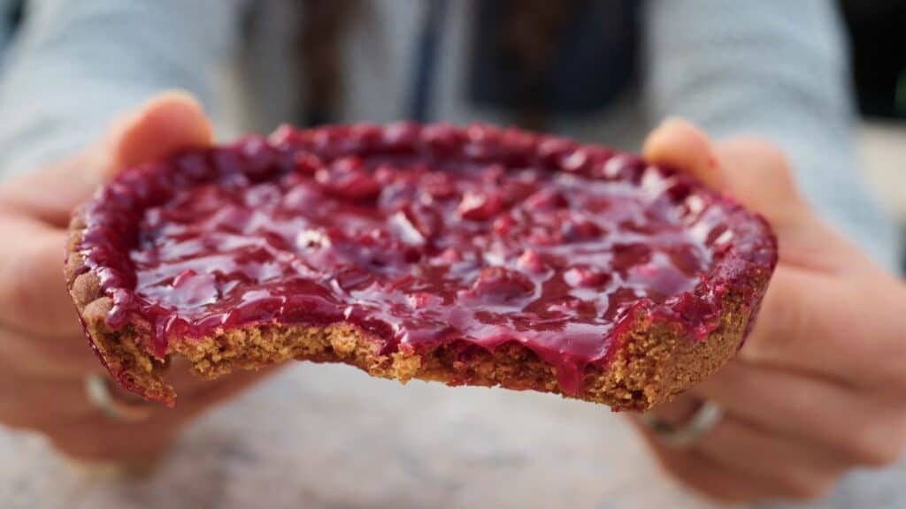 Tarte aux pralines with bright pink praline filling, partially eaten to show the texture