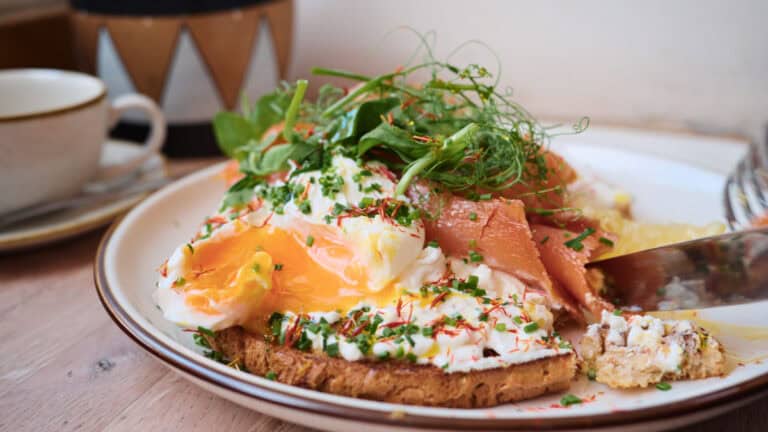 Poached eggs and smoked salmon on toast topped with fresh herbs at a brunch café in Edinburgh