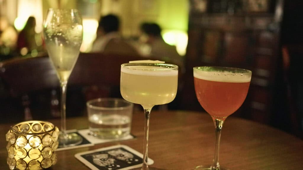 Two craft cocktails on a table inside a dimly lit Edinburgh cocktail bar