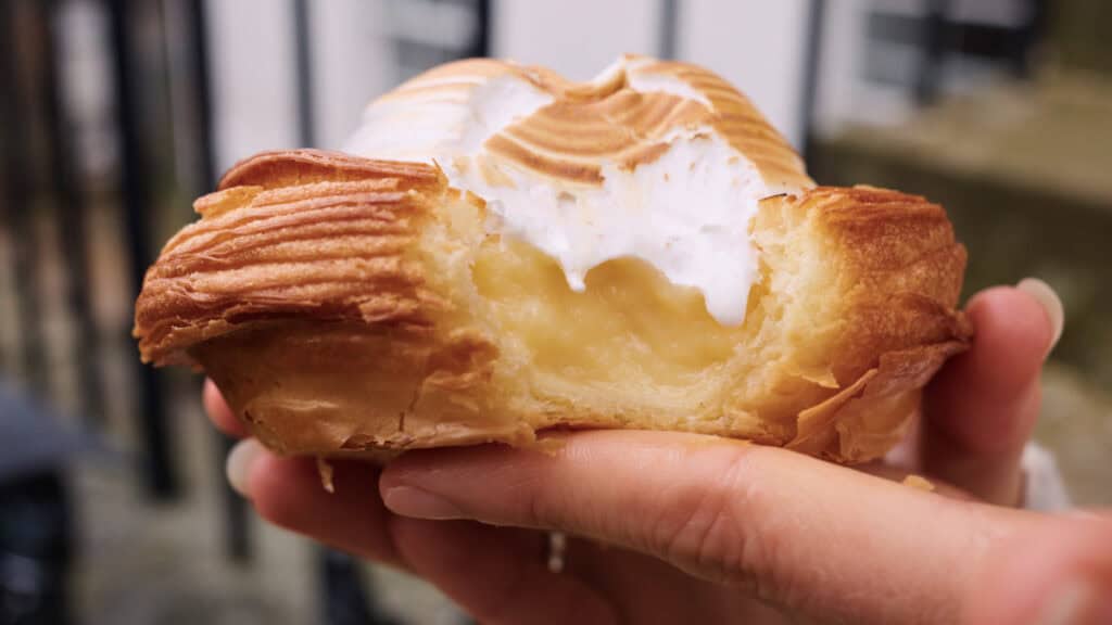 Close-up of a flaky pastry filled with lemon cream and topped with toasted meringue from an Edinburgh bakery