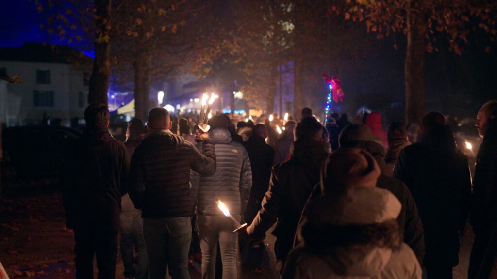 Torchlit night procession in a French town during a local cultural festival