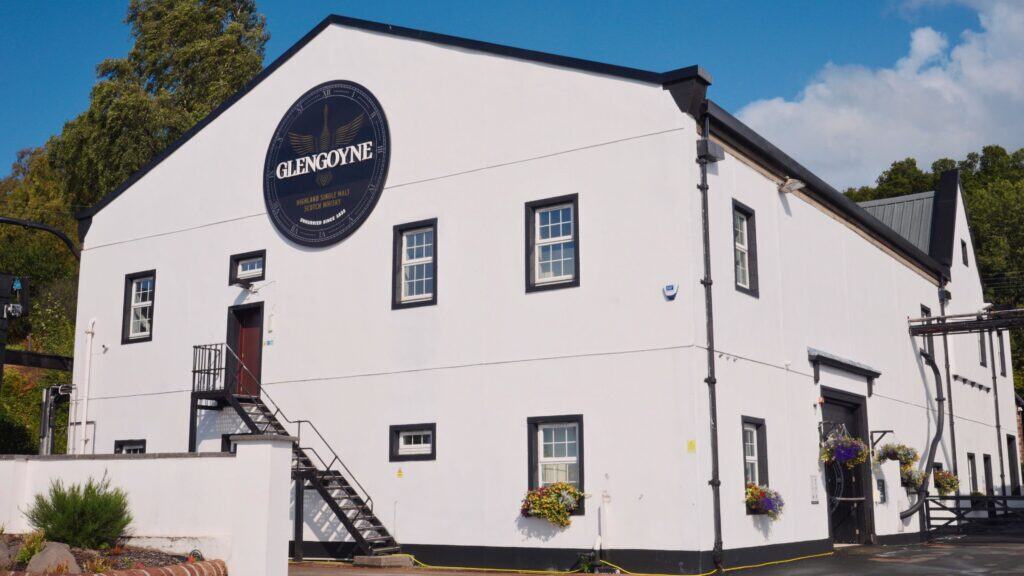White building with a large circular sign reading “Glengoyne Highland Single Malt Scotch Whisky.” The distillery exterior represents Scotland’s world famous whisky industry tied closely to traditional Scottish food and drink traditions.