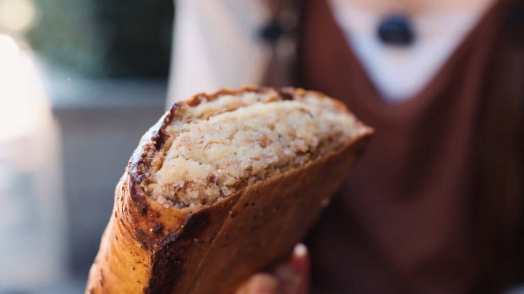 Close up of a baked pastry with a golden crust and soft layered interior, illustrating the comforting baked side of traditional Georgian foods.